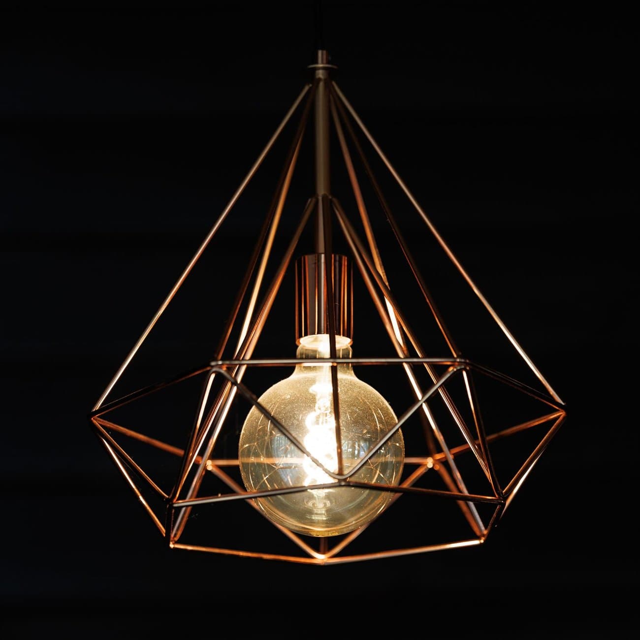 Sculptural geometric pendant light glowing against a black backdrop