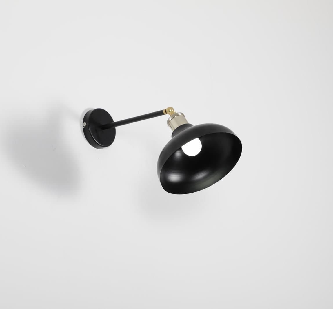 Minimal black surface-mounted lamp casting a soft shadow on a white wall
