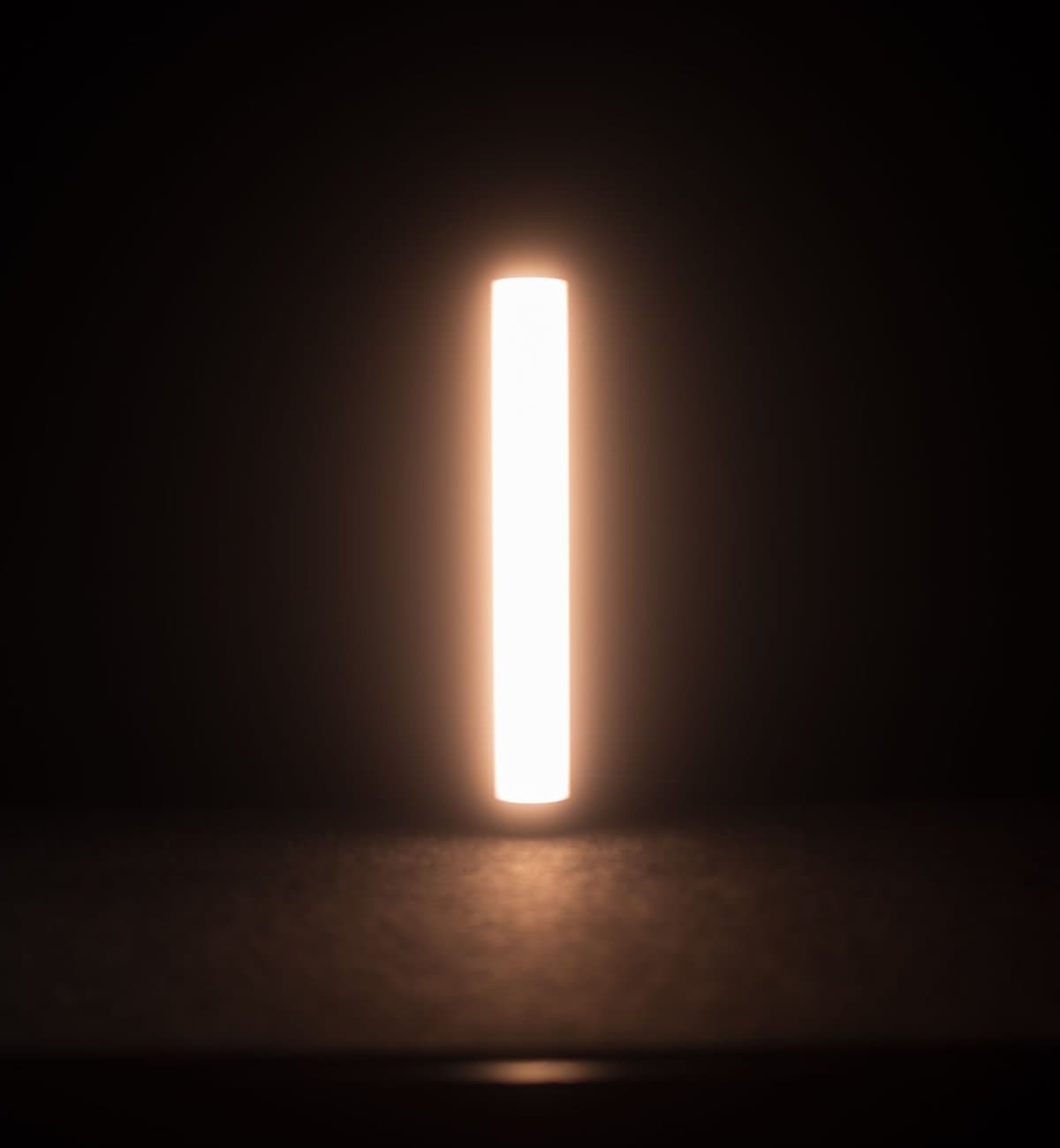 Ultra-slim vertical light bar glowing warm white against a dark background